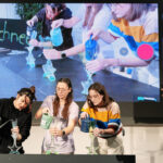 3 Frauen auf Bühne gießen Flüssigkeiten in Behältnisse. 1 Frau filmt das.